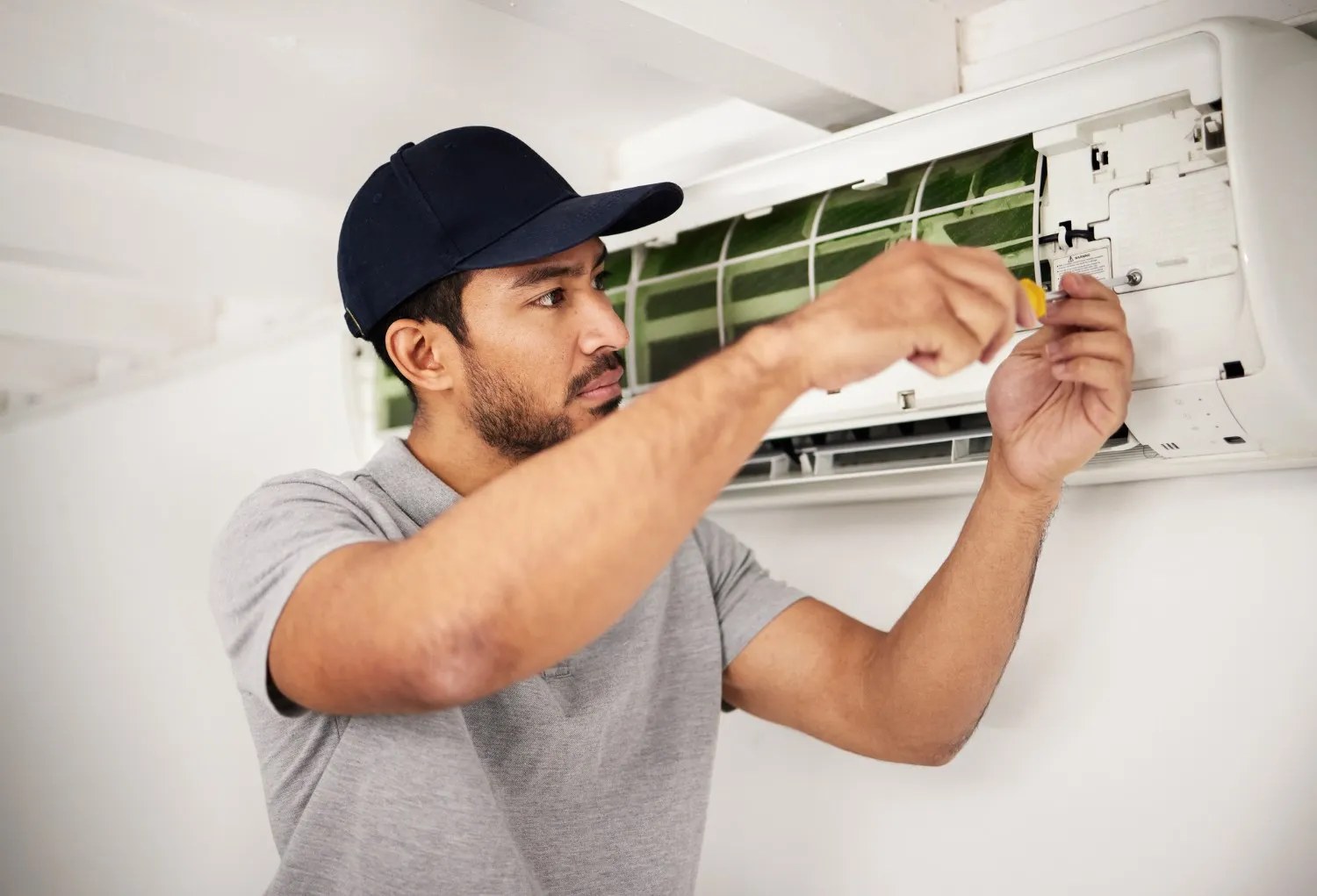 Technician fixing air conditioner with a screwdriver.