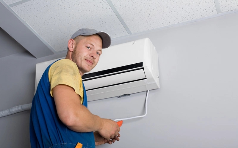 Technician posing next to AC unit.