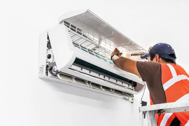 Technician in vest inspecting ductless AC.