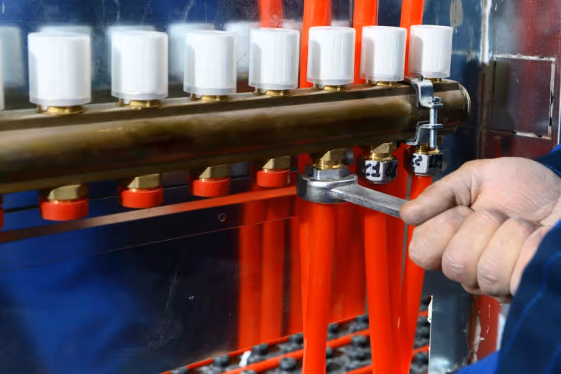 Hand using wrench on radiant heating manifold