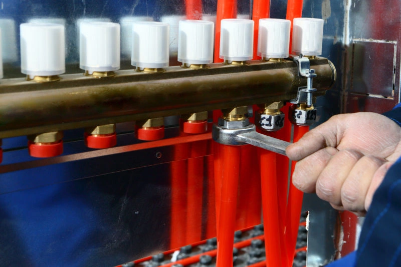 Hand using wrench on radiant heating manifold
