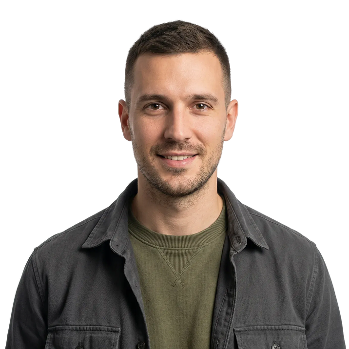 Smiling man with short dark hair wearing a dark jacket over an olive green shirt.