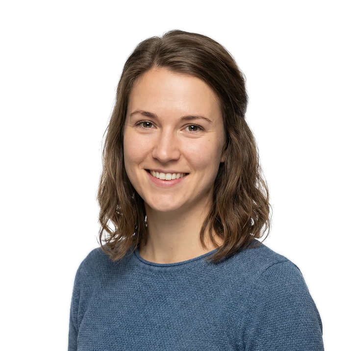 Smiling woman with shoulder-length wavy brown hair wearing a blue sweater.