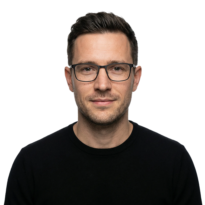 Portrait of a man with short dark hair, wearing glasses and a black shirt, against a black background.