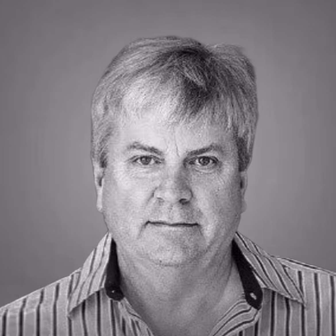 Black and white headshot of a middle-aged man with short gray hair wearing a striped shirt.