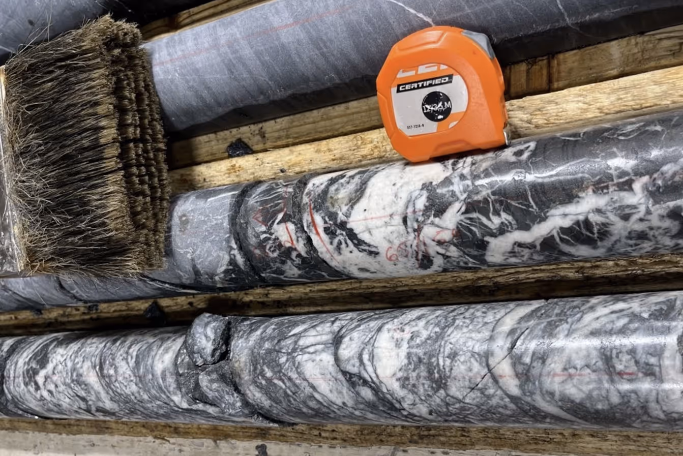 Marble rock core samples with marked measurements and an orange tape measure placed on wooden trays.