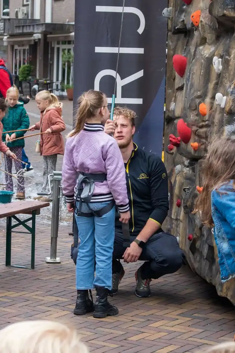 Instructeur die uitleg geeft aan een kind bij de mobiele klimwand