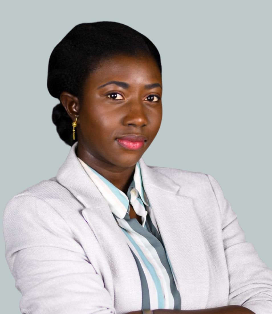 Confident woman with dark hair in a light blazer and striped shirt, posing with arms crossed against a light gray background.