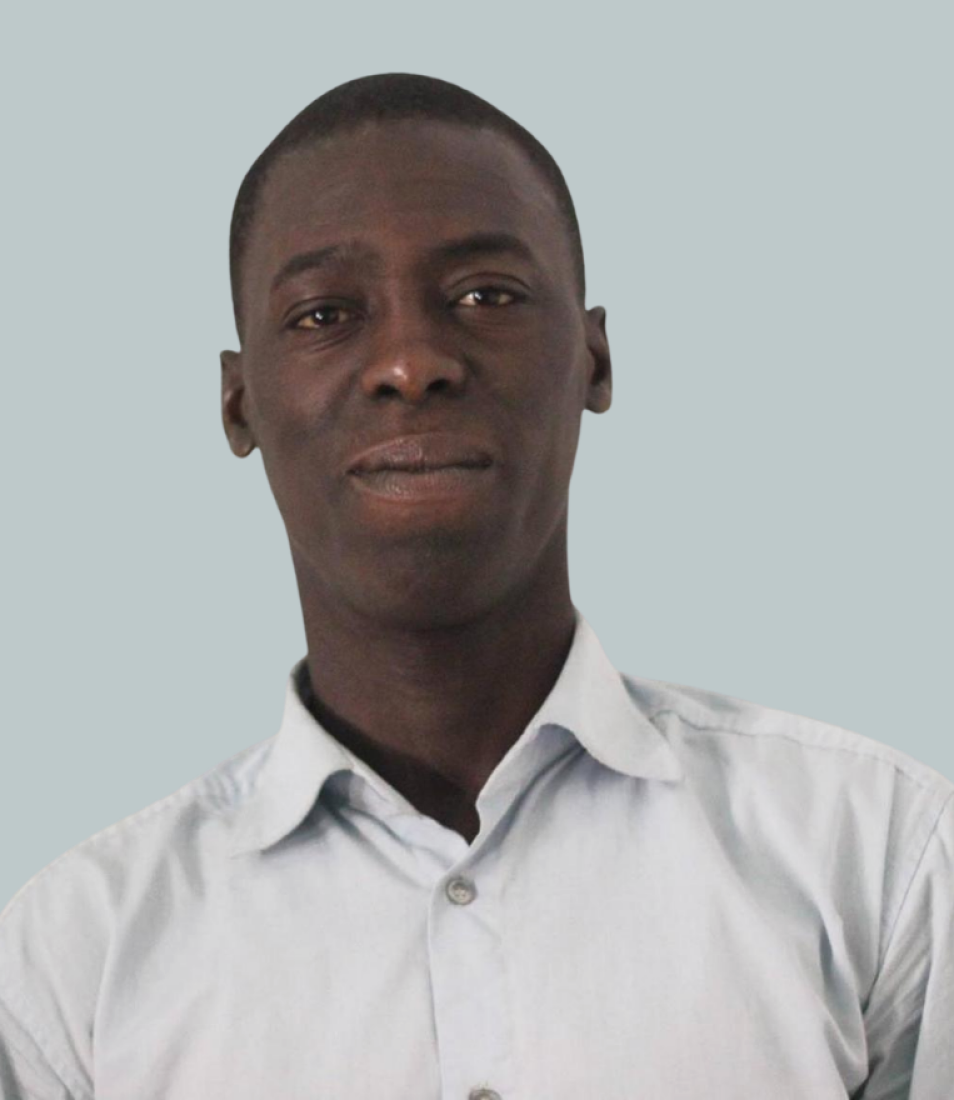 Portrait of a man wearing a light blue buttoned shirt against a plain light gray background.