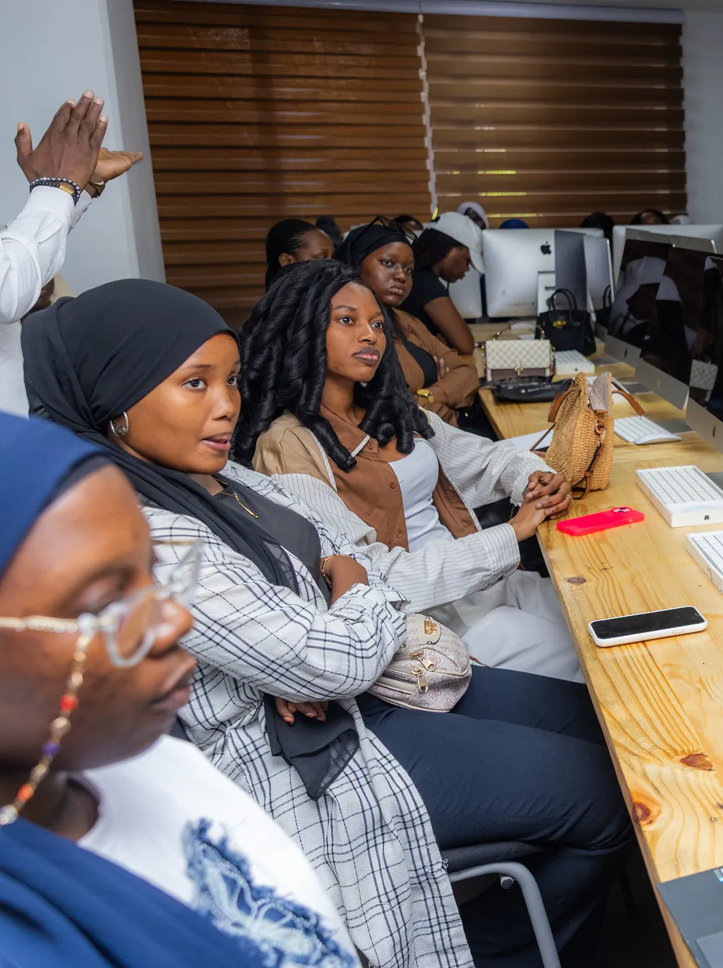 Photo of a phone screen showing a woman sitting on a yellow chair with a microphone in front, holding a phone, with camera settings visible around the image.