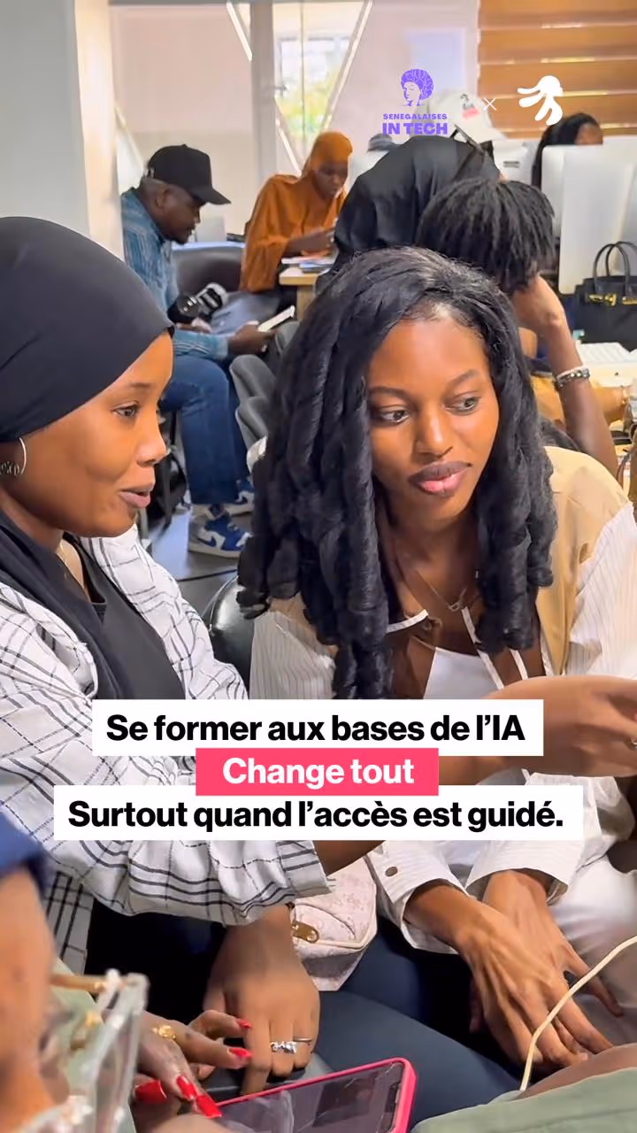 Two women discussing while looking at a smartphone, with others working in the background.