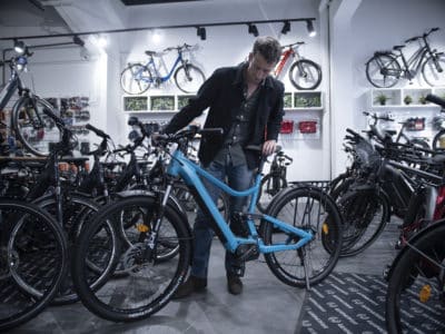Homme qui essaie un vélo bleu dans un magasin de vélos