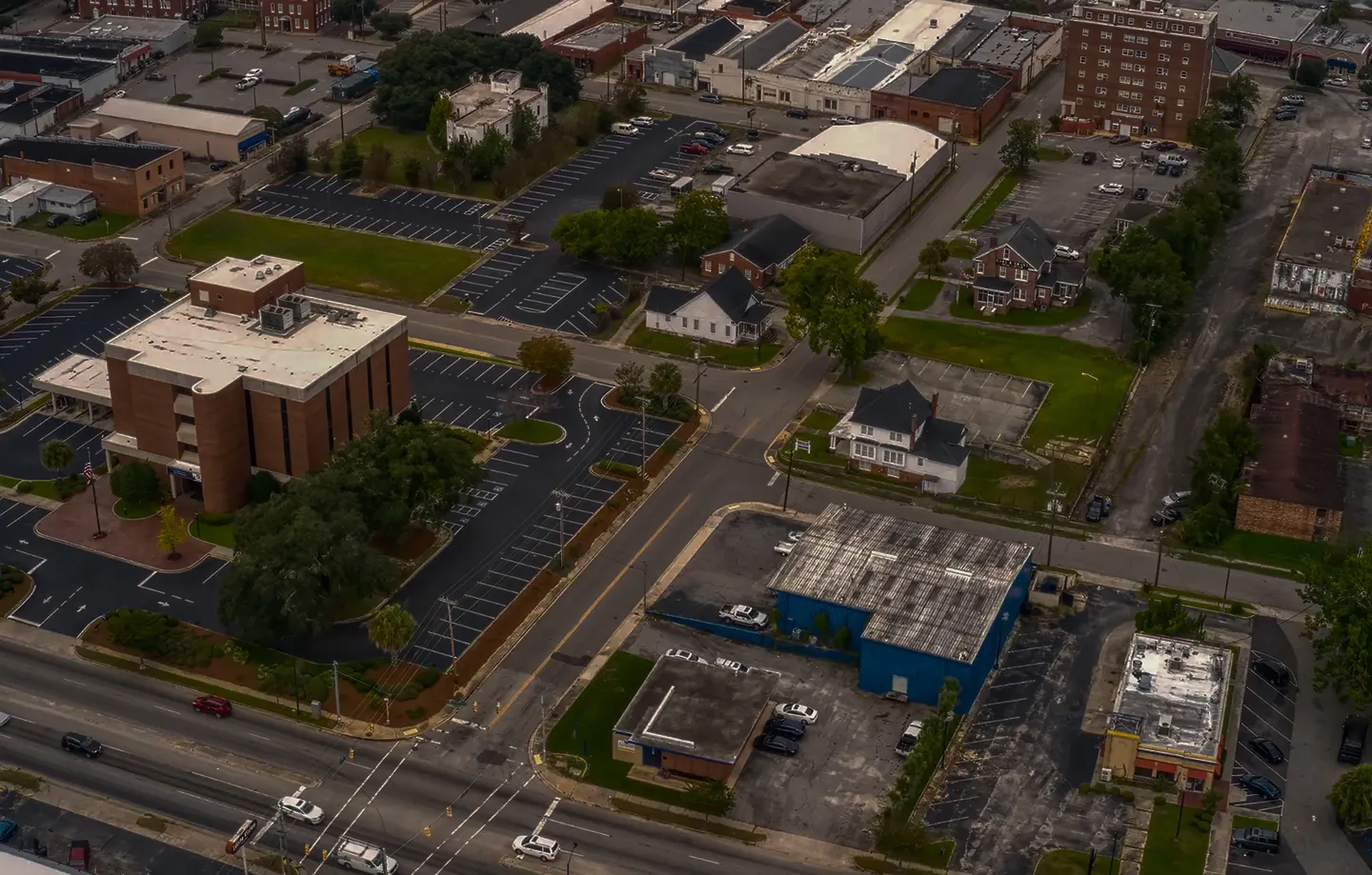 Aerial view of an urban intersection with multiple buildings, parking lots, and roads.