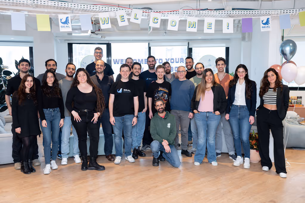 Group of 20 people posing indoors under a 'WELCOME!' banner with balloons and a SEAL Security logo.