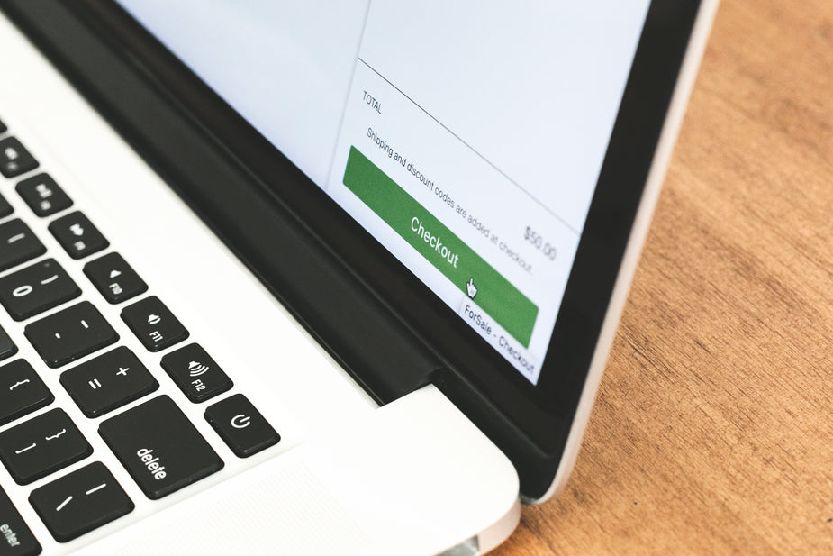 Close-up of a laptop keyboard and screen showing a green Checkout button for an online purchase totaling $50.00.