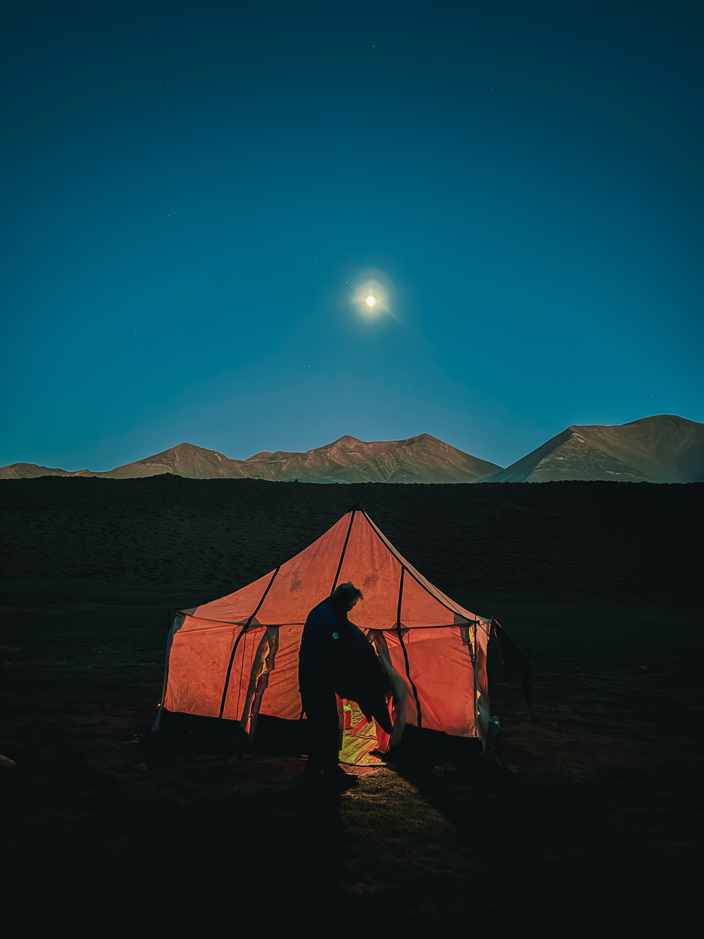 bivouac rouge isolée sous la lune, montagnes de l'Atlas en arrière-plan durant l'asencion de djbel mjoun trekking et rando au Maroc.