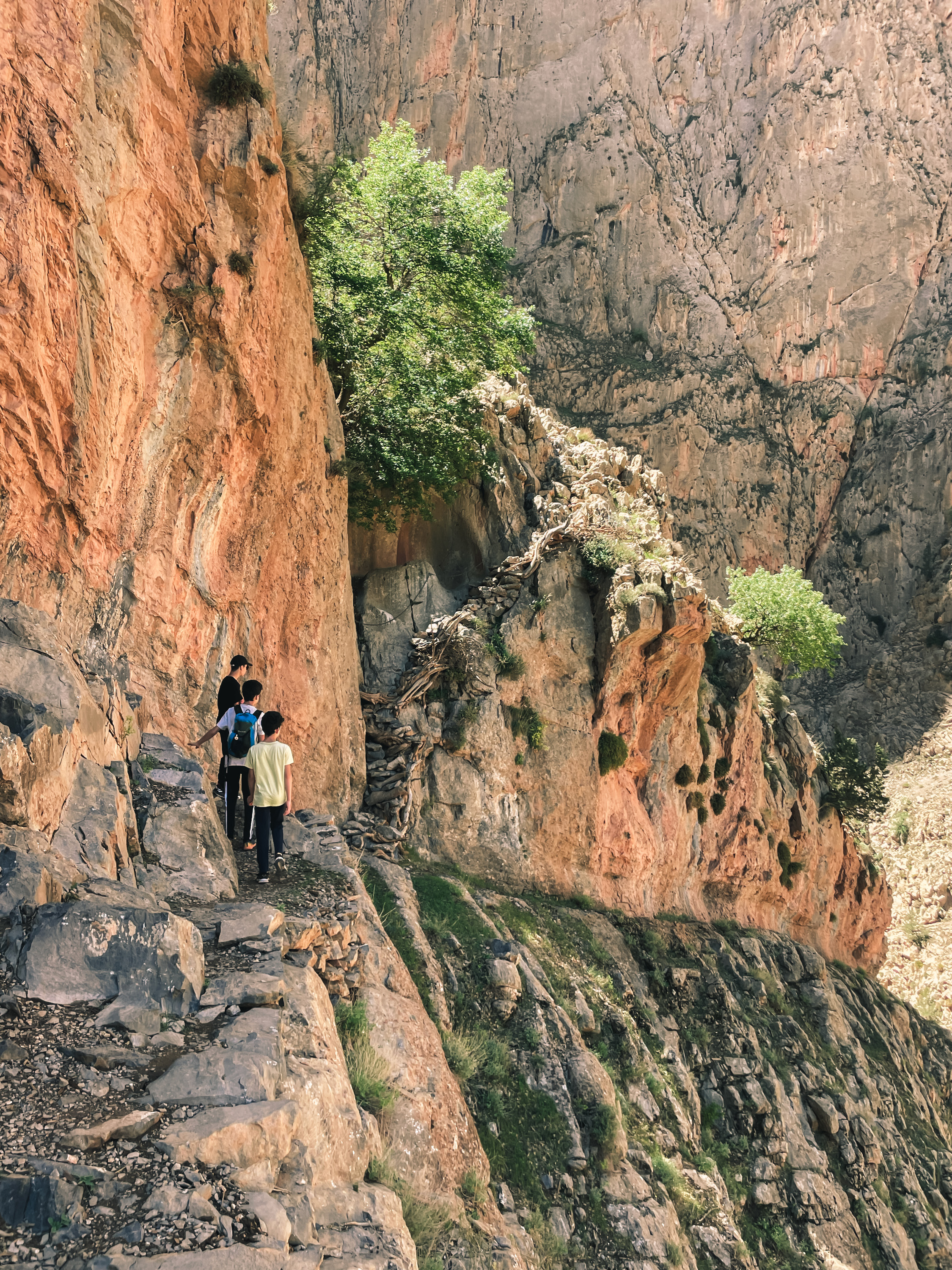 Randonneurs sur un sentier étroit entre des falaises rocheuses dans l'Atlas marocain