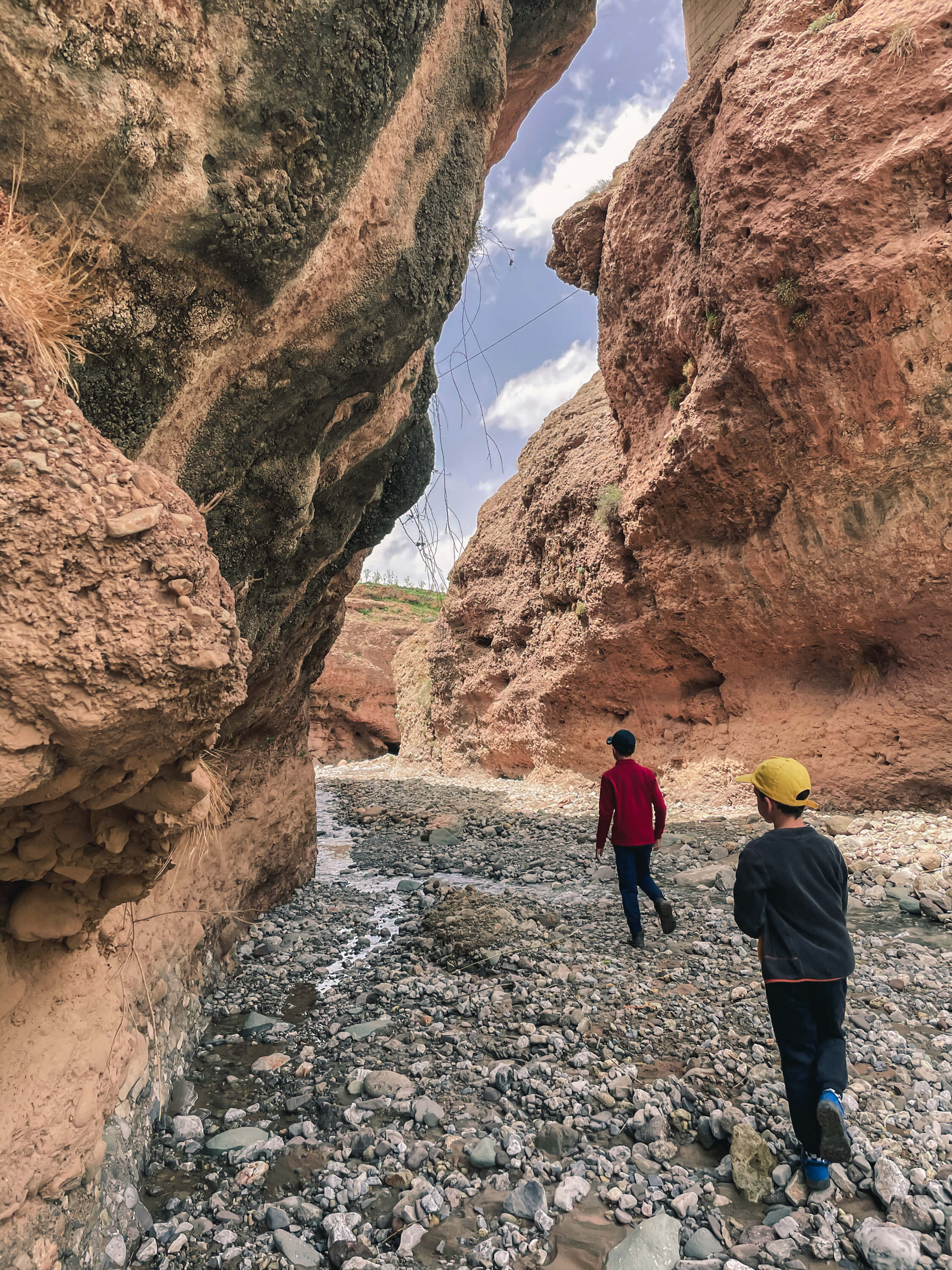 Deux randonneurs marchent entre des rochers rouges dans une vallée rocheuse