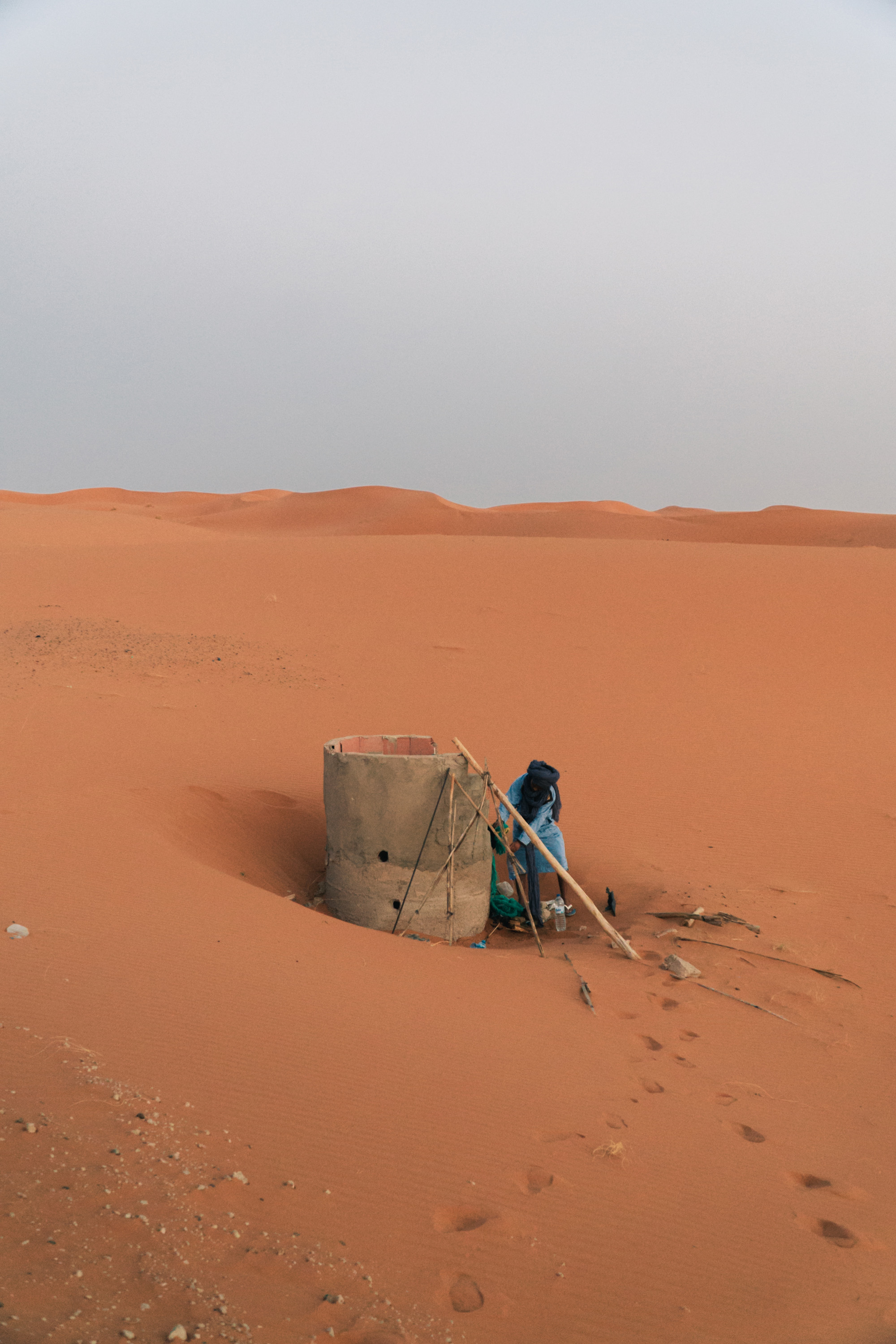 Personne près d'un puits dans les dunes orangées du désert marocain