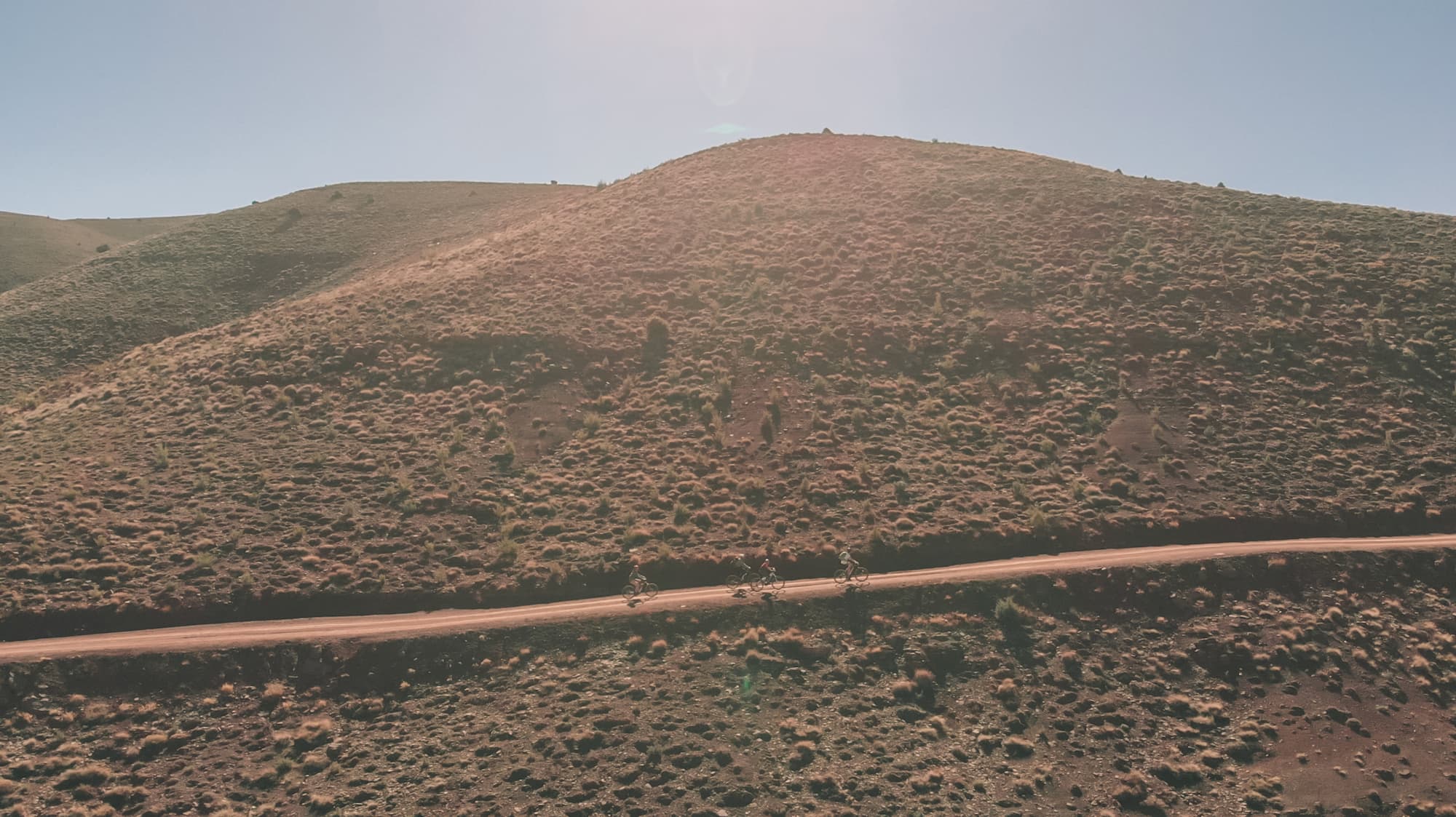 Cyclistes solitaires sur une route poussiéreuse traversant les montagnes de l'Atlas marocain