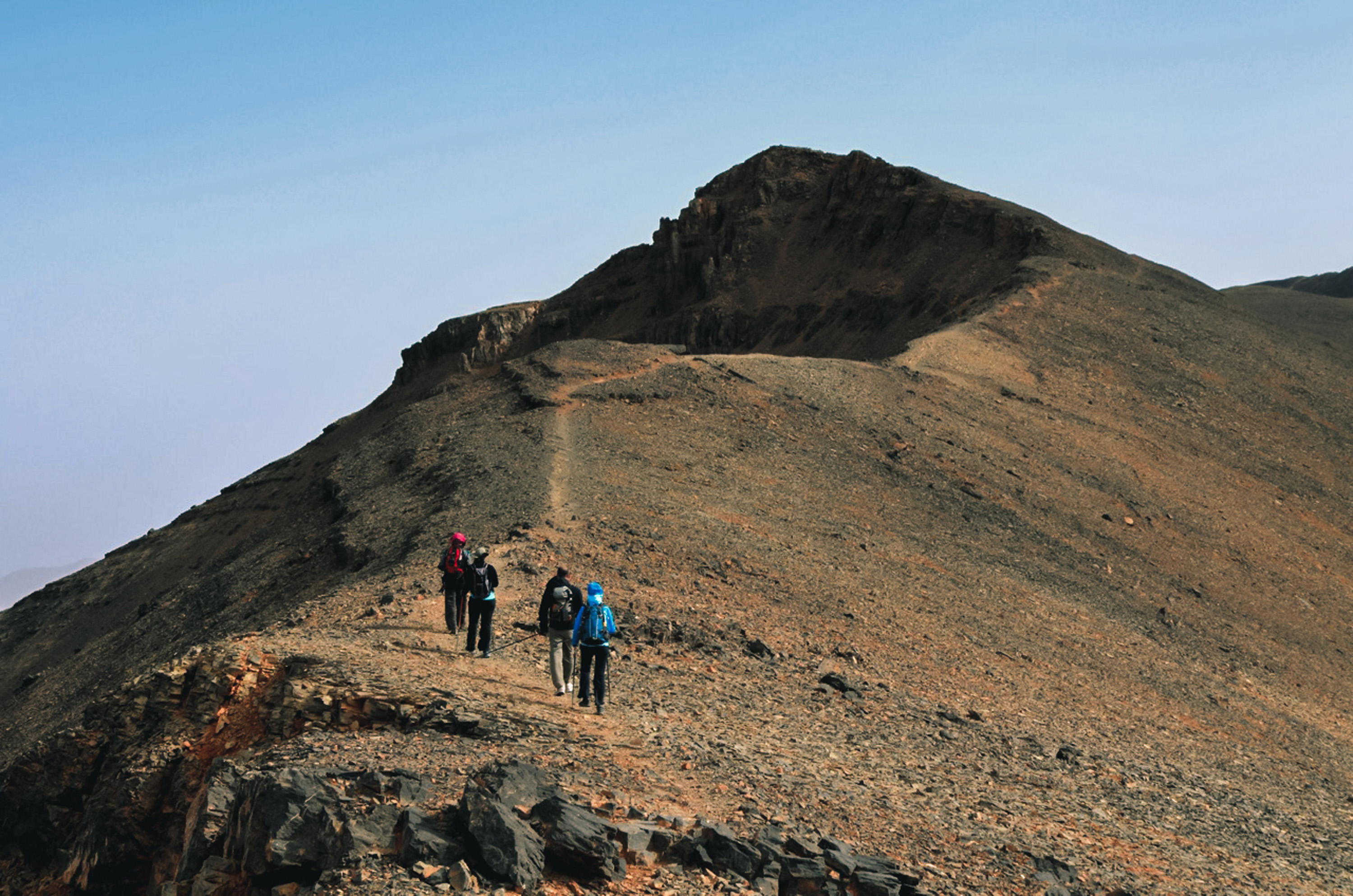 Randonneurs dans le Haut Atlas marocain gravissant un sentier rocailleux escarpé
