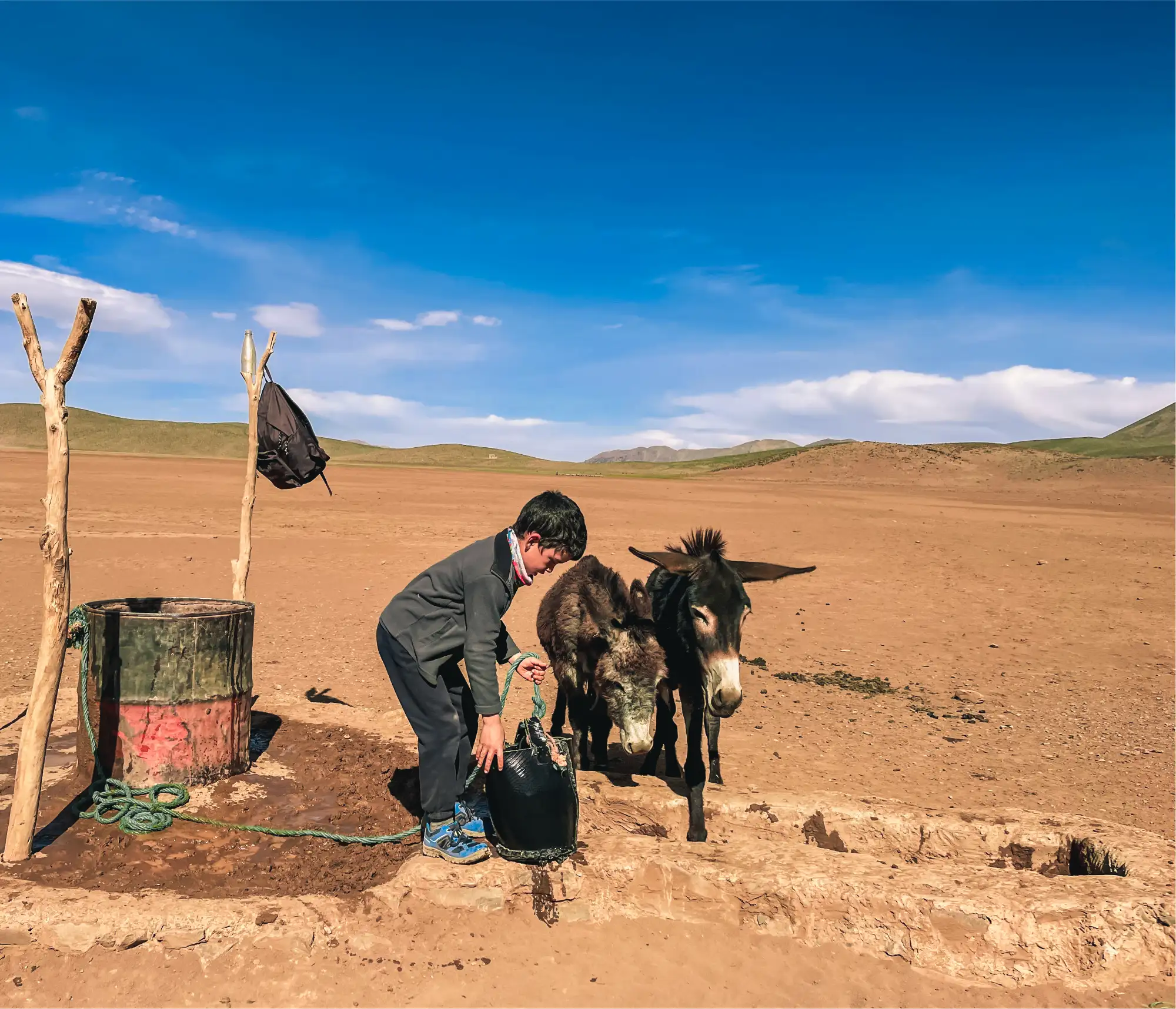 Âne et personne près d'un tonneau dans un paysage désertique marocain aride