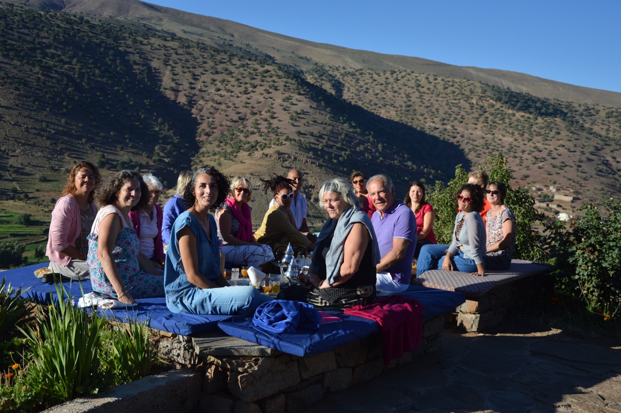 Groupe de voyageurs de touda ecolodge prenant le thé avec vue panoramique sur la vallée bougemez de l'Atlas marocain