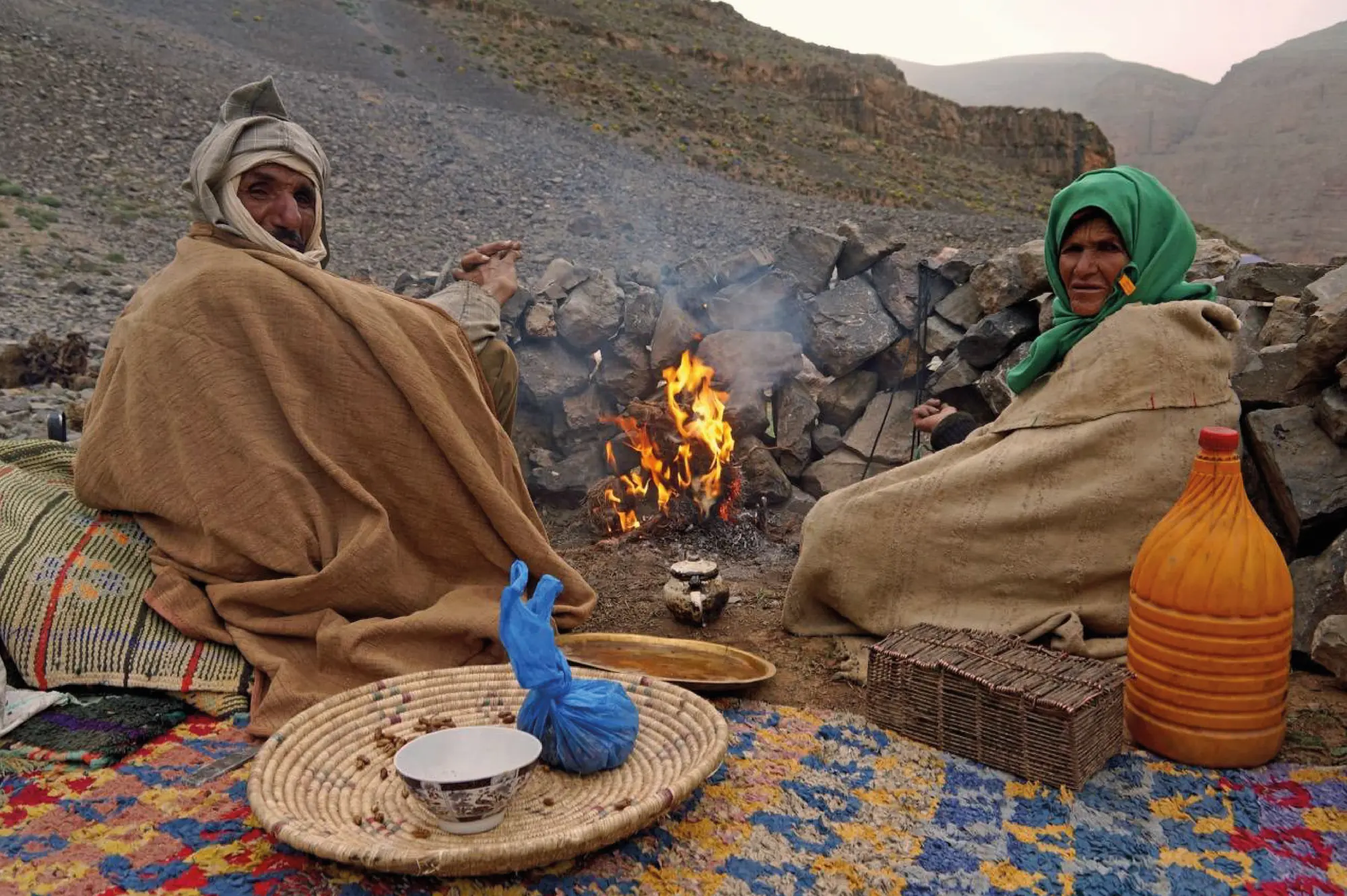 Couple de nomades Aït Atta réchauffé autour d'un feu de camp au bivouac, lors de la transhumance dans le Haut Atlas marocain