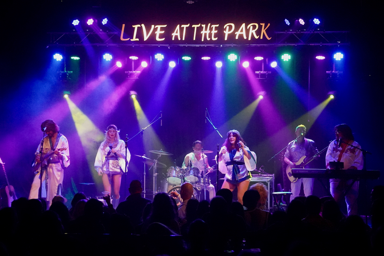 A tribute band performs for a packed room under the Live at the Park sign at the Park Theatre in Holland, Michigan