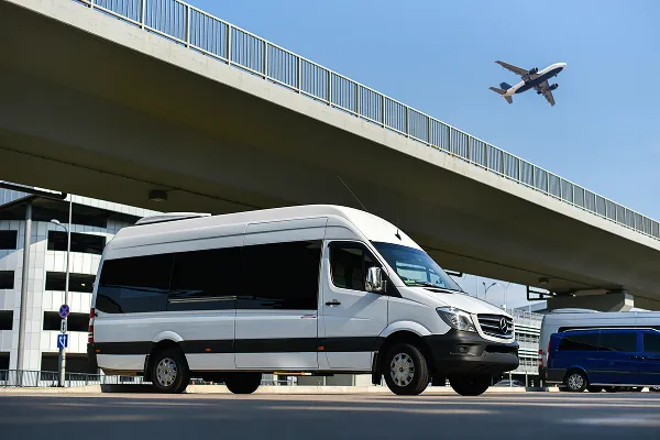 A white van and a blue van under a bridge.
