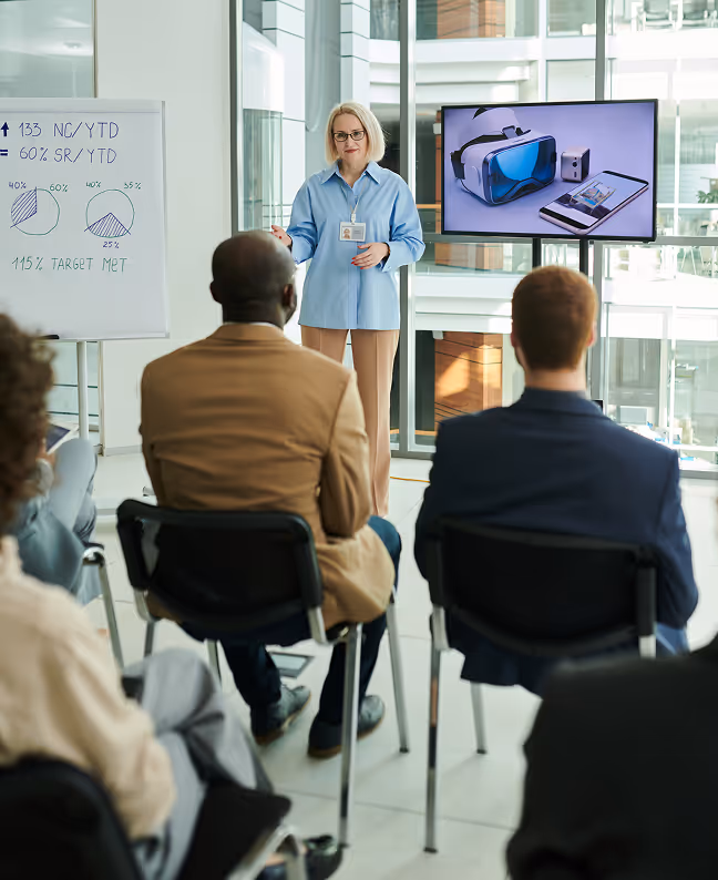 A businesswoman giving a presentation about virtual reality to an attentive audience in a modern office.