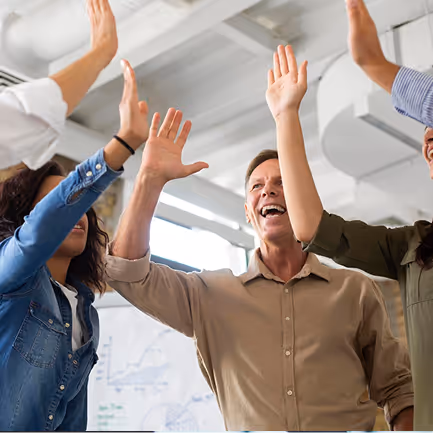 Group of diverse people in an office raising their hands for a high five in celebration.