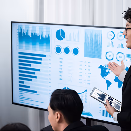 Businesswoman presenting data charts and graphs on a large screen to colleagues in a meeting room.