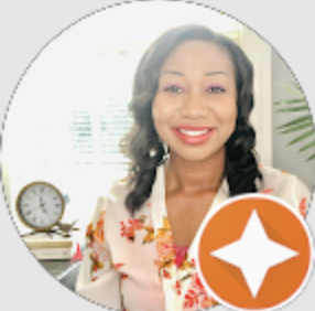 Smiling woman with dark hair wearing a floral blouse, sitting indoors near a clock and a plant.