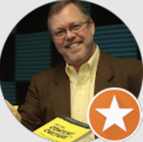 Smiling man wearing glasses and a brown jacket holding a book titled 'Channel Marketing'.