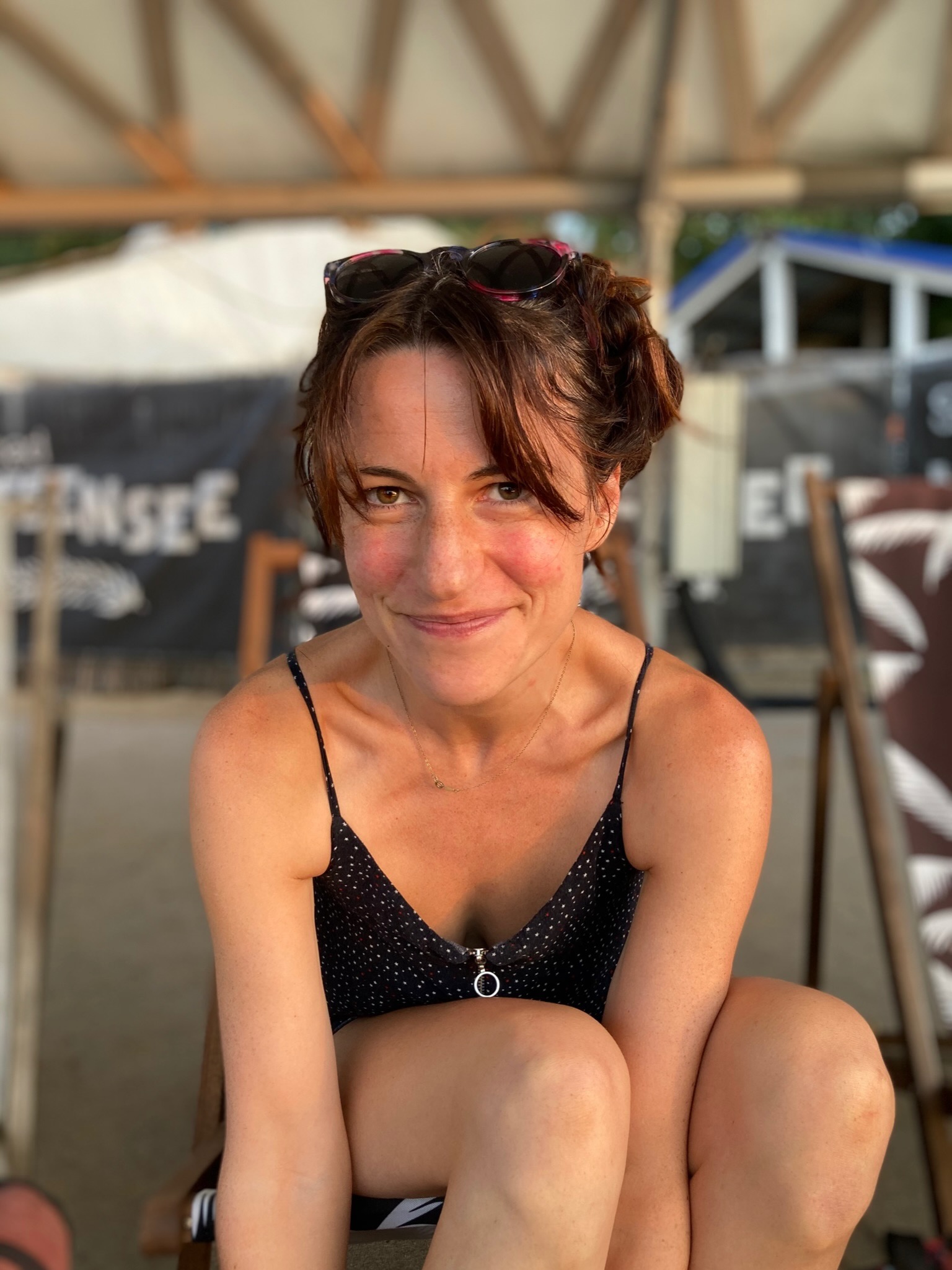 Frau in Sommerkleidung sitzt nach vorne gebeugt auf einem Liegestuhl