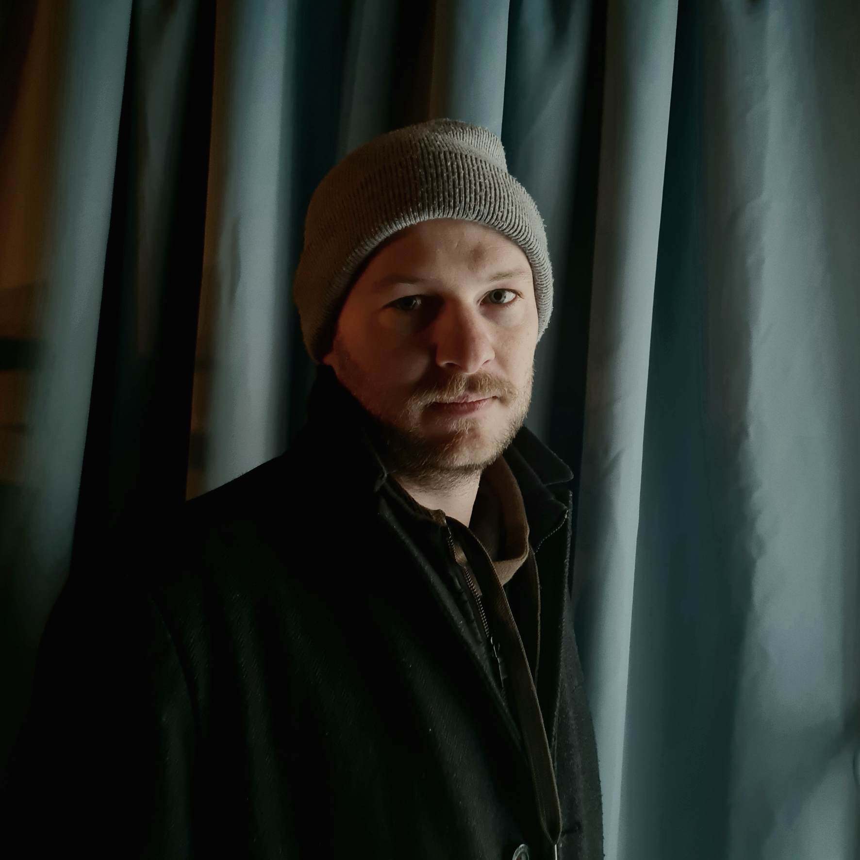 Porträtfoto von Alexander Rudolfi in grauer Mütze und schwarzer Jacke