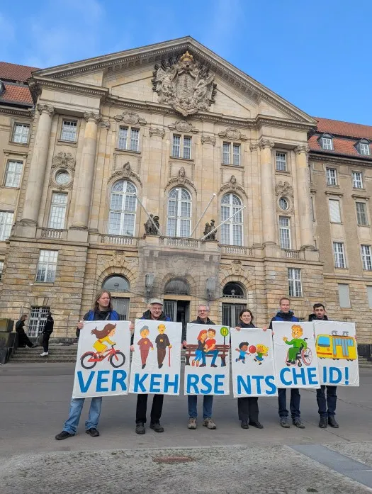 Eine Gruppe von sechs Demonstrierenden hält Schilder in die Luft, die gemeinsam den Schriftzug "Verkehrsentscheid" bilden.