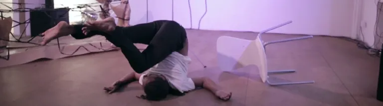 Auf dem Boden turnende Person neben einem umgekippten Stuhl