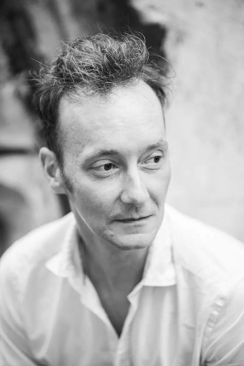 Schwarzweiß-Porträt eines schlanken Mannes mit dunklen Haaren und weißem Hemd