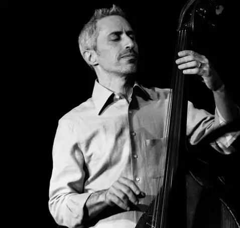 Schwarzweiß Porträtfoto von Gidi Farhi. Er spielt stehend einen Kontrabass.