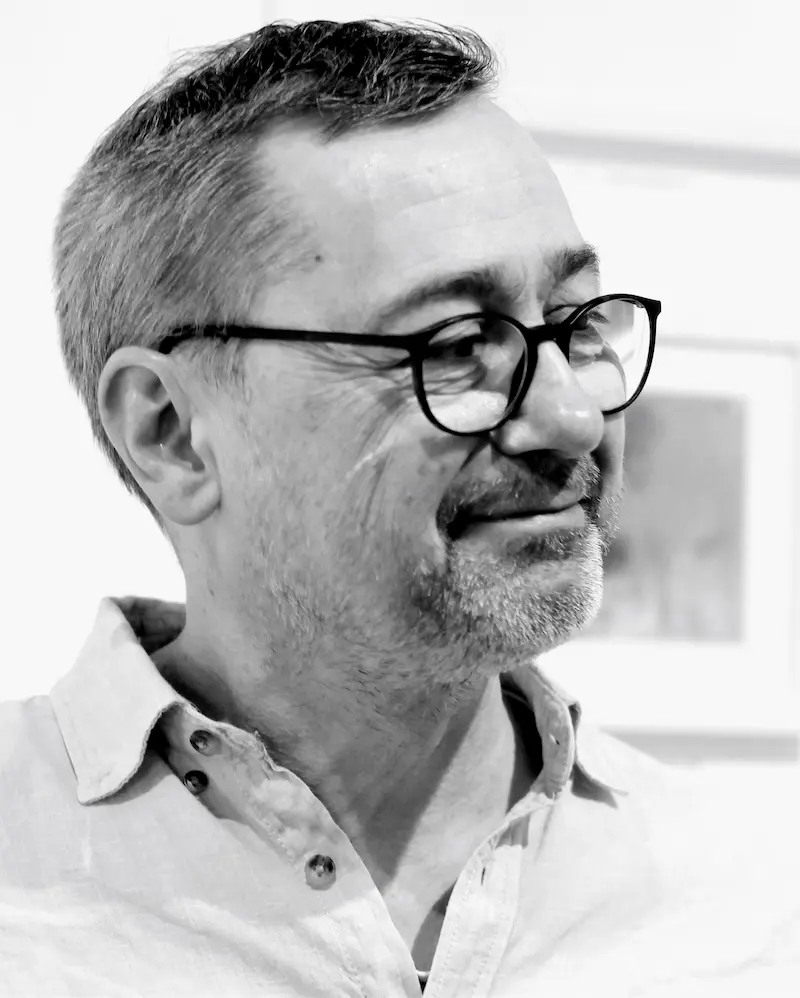 Schwarz-weiß-Porträt von Michael Wäser, er trägt Brille und ein helles Hemd mit offenem Kragen