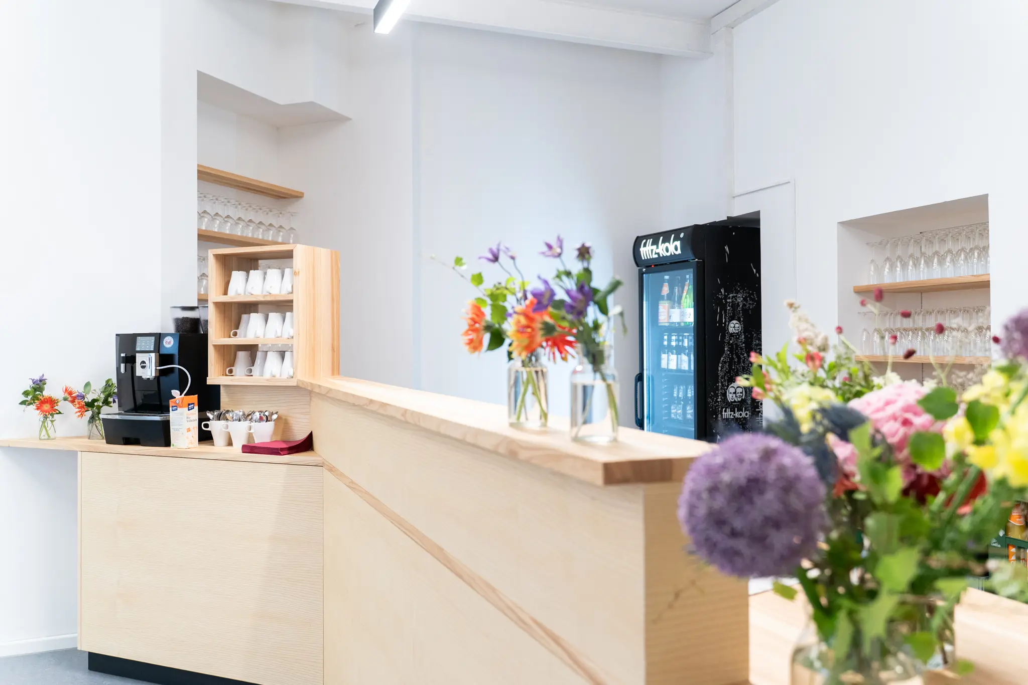 Bartheke aus Holz mit Kaffeeautomat, Kaffeetassen und Blumensträußen