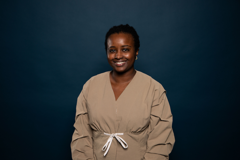 portrait of the artist wearing a beige dress, dark blue background