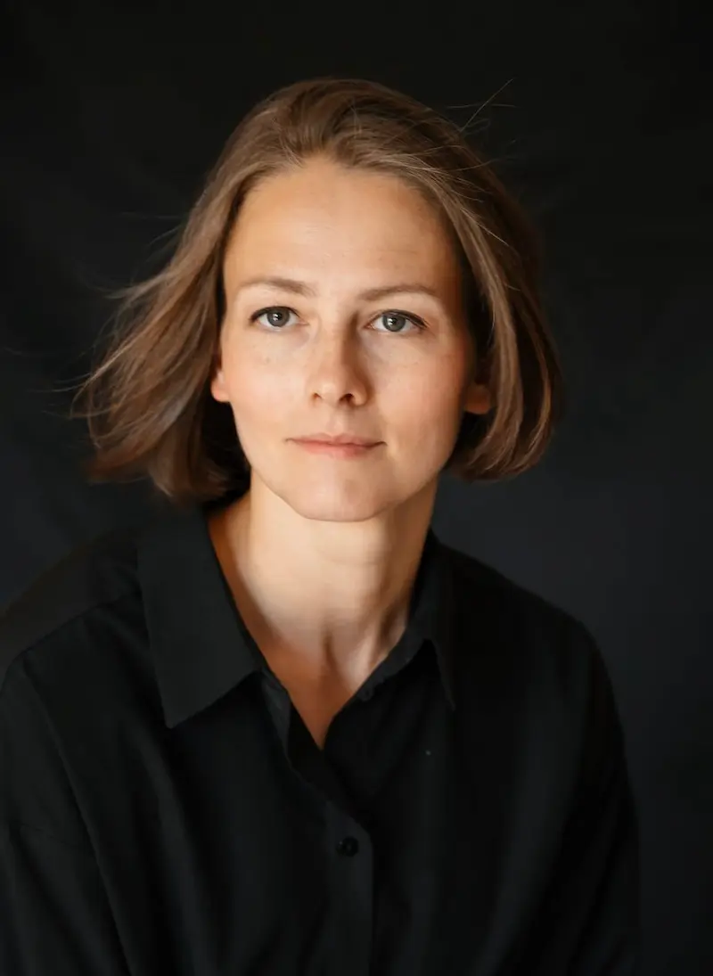 Portrait of the artist wearing black shirt, black background