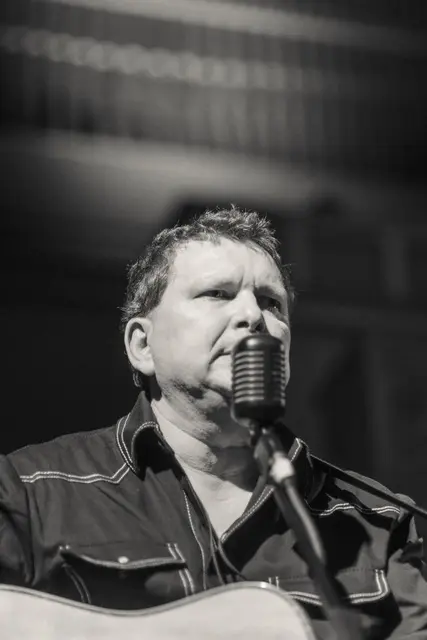 Schwarz-weiß-Foto von Marc Ottiker, der in ein Mikrophon singt