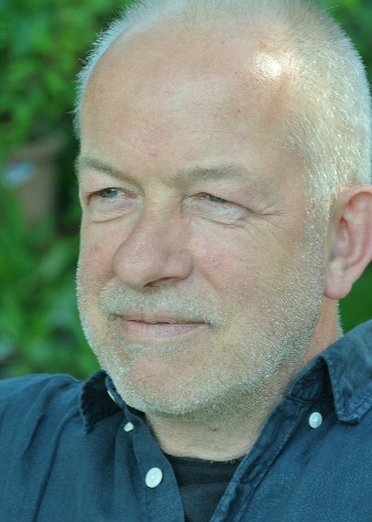 Magnus Tautz hat kurze weiße Haare und einen Dreitagebart; er trägt ein blaues Jeanshemd.