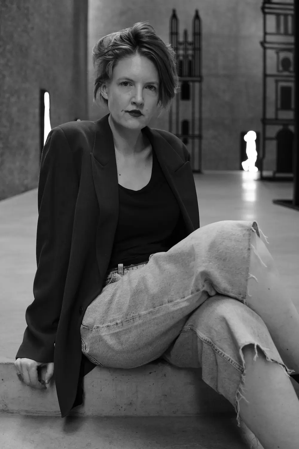 Mara Genschel sitzt mit übereinander geschlagenen Beinen auf einer Betonstufe.