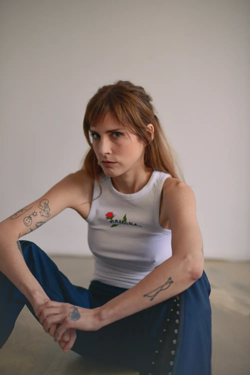 Paulina Flores sitzt breitbeinig auf dem Boden und hat die Ellbogen auf den Knien abgelstützt