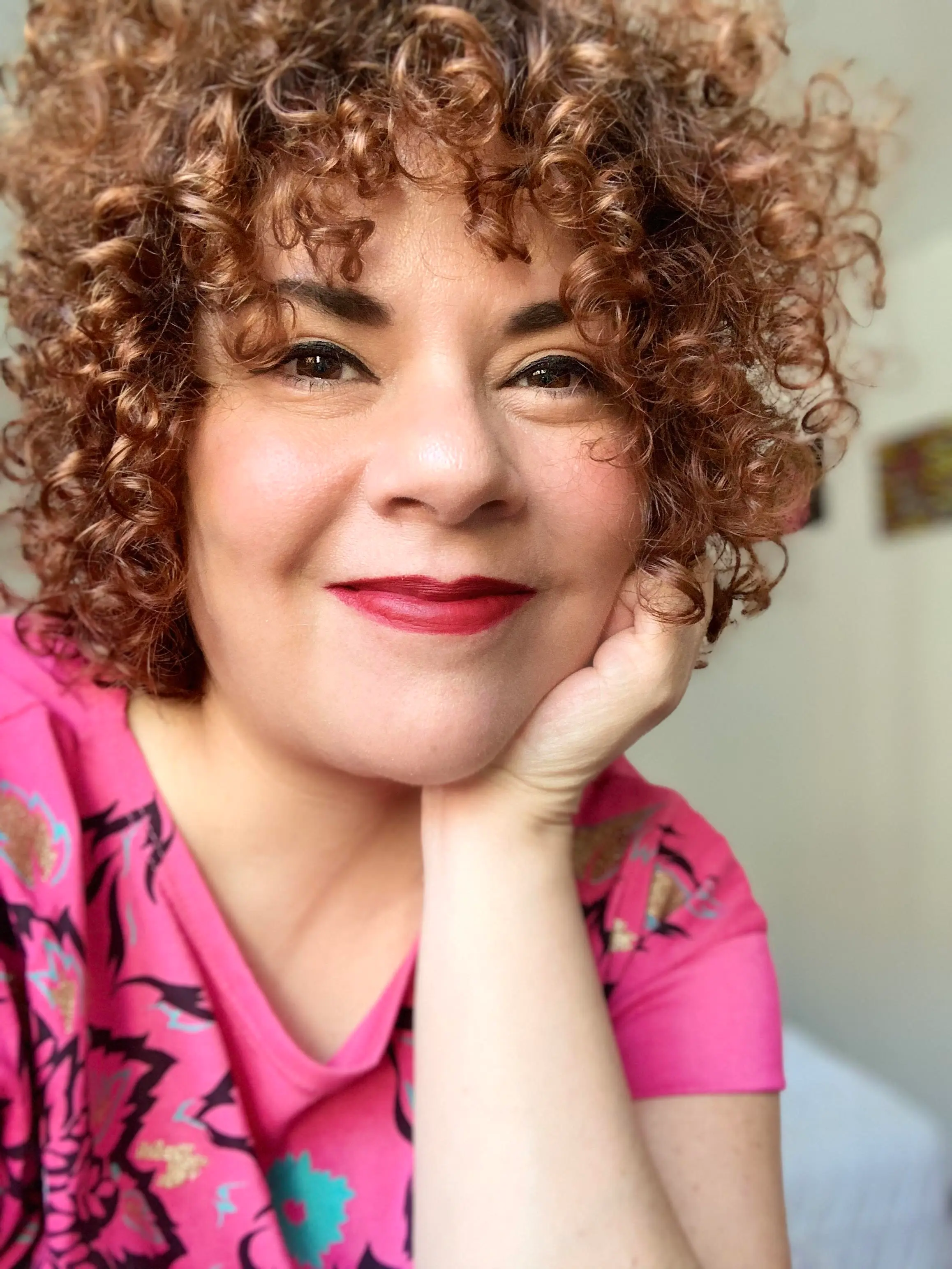 María Fernanda Ampuero hat ihr Kinn auf die Hand gestützt und lächelt in die Kamera